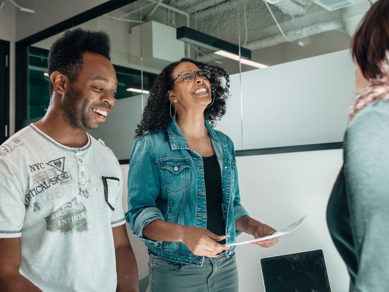 Two people smiling together as they look over a printed document.